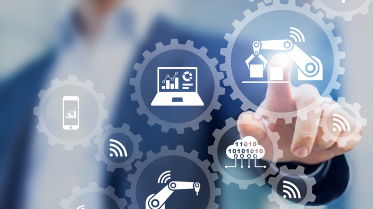 Smart factory and industry 4.0 concept with connected production robots exchanging data with internet of things (IoT) and cloud computing technology, businessman touching interface with icons in gears